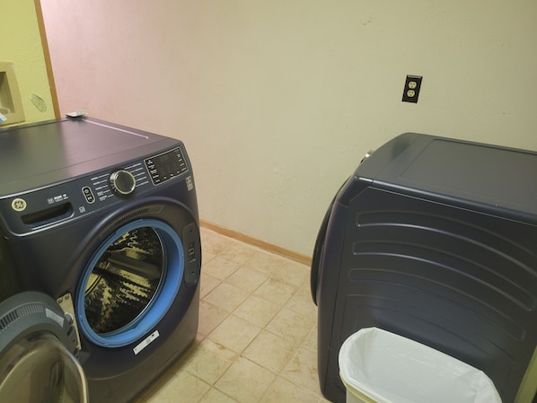 A laundry area with a front-loading washing machine and a stacked washer and dryer unit.