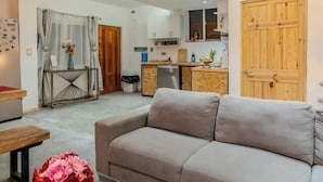 A modern living room with a sofa, a coffee table with flowers, and a kitchen in the background. - Luxury Home 2_Starlink 400 Mbit_AC_Jacuzzi_6 People (San Juan del Obispo)