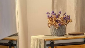 A workspace with a glass table, keyboard, mouse, and a vase of dried flowers. - Luxury Home 2_Starlink 400 Mbit_AC_Jacuzzi_6 People (San Juan del Obispo)