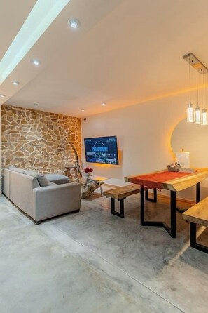 A modern living room with a stone accent wall, a flat-screen TV, a pool table, and a sofa. - Luxury Home 2_Starlink 400 Mbit_AC_Jacuzzi_6 People (San Juan del Obispo)