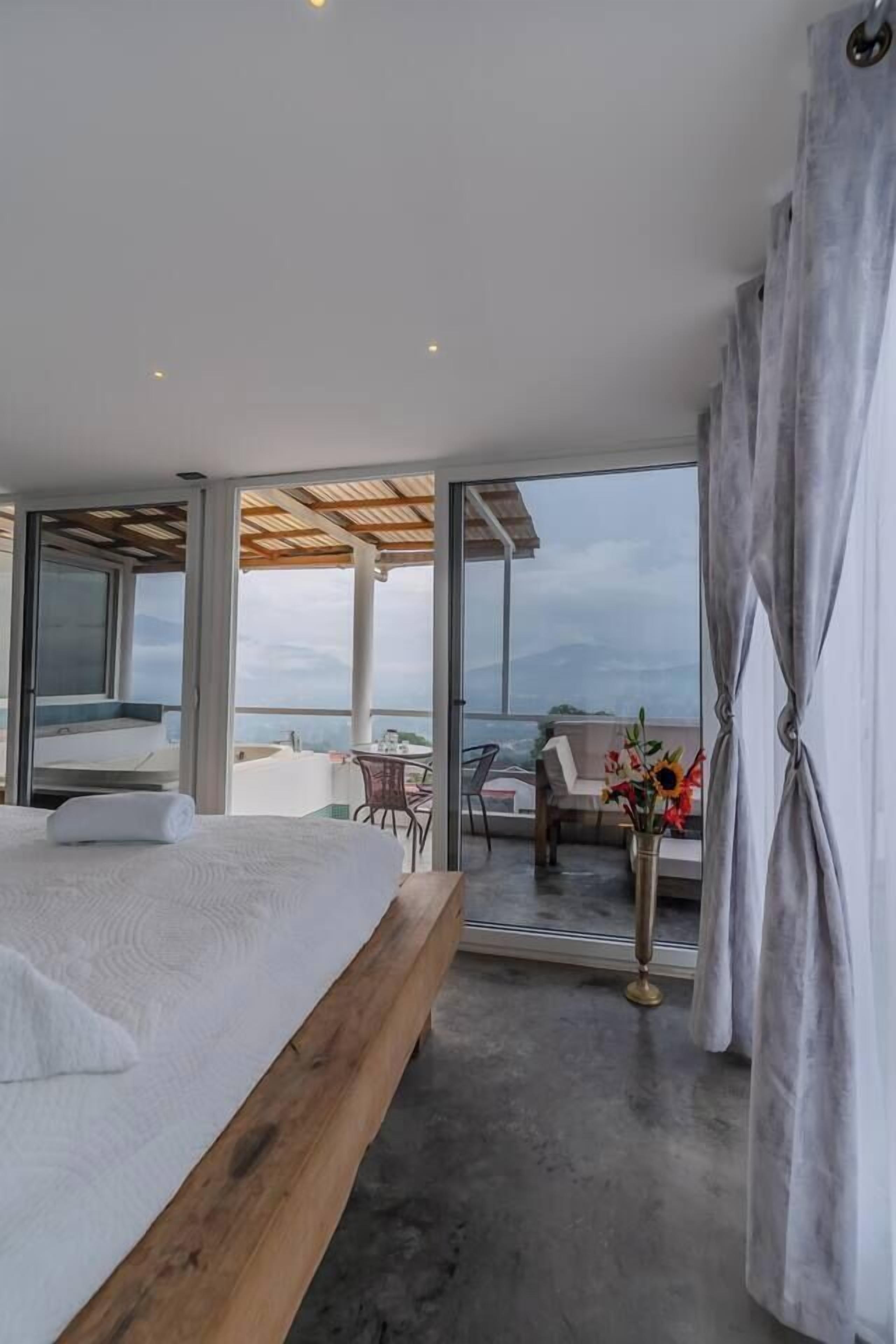 Une chambre avec un grand lit, un balcon avec vue et un coin repas.