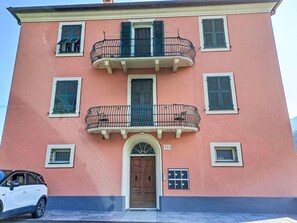 A building with a pink facade, a central entrance with a wooden door, and multiple windows with shutters. - La Casa di Tea by Interhome (Borzonasca)