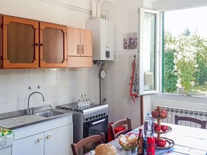 A compact kitchen with a sink, stove, and cabinets. There is a window with a view of trees outside. - La Casa di Tea by Interhome (Borzonasca)