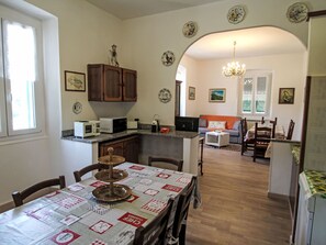 A kitchen with a dining table, chairs, and a microwave. There is a sofa and a dining table in the background. - La Casa di Tea by Interhome (Borzonasca)