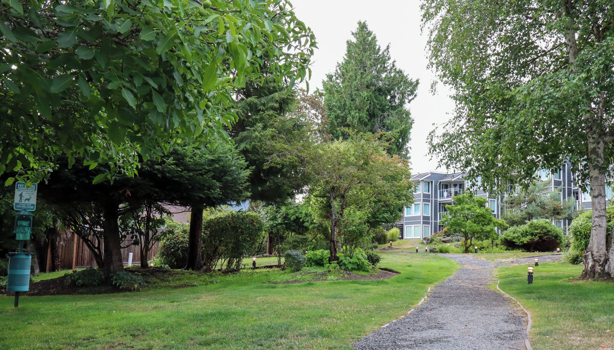 Un chemin menant à un bâtiment doté d’un jardin et d’arbres bien entretenus.