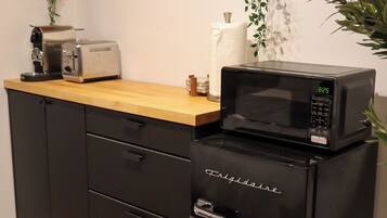 Una kitchenette con microondas, tostadora y armarios.