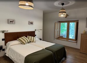 A bedroom with a double bed, two bedside tables, a window with shutters, and a view of greenery outside. - Salto del Ciervo Private Estate in the natural setting of the Sierra de Cuenca (Priego)