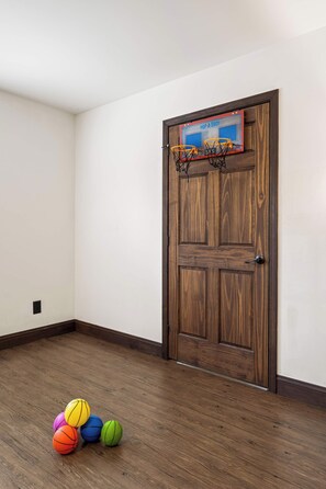 Ein Raum mit einer Holztür, einem Basketballkorb und mehreren Basketballs auf dem Boden.