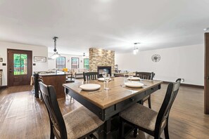 A spacious dining area with a large wooden table set for six, surrounded by dark wooden chairs with cushioned seats. - Maplecrest Retreat | Firepit • Hot Tub • Game Room (Sevierville)