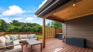 Eine überdachte Terrasse mit Sofa, Tisch und Grillbereich.