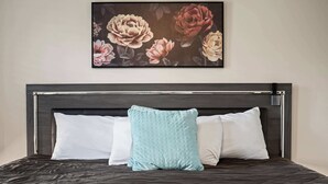 Ein Bett mit dunkelbrauner Kopfteil, zwei weiße Kissen und ein hellblaues Kissen.