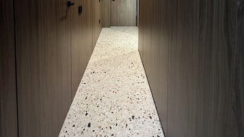 Ein Korridor mit Holzwandverkleidung und einem punktierten Boden, der zu einer Tür führt.