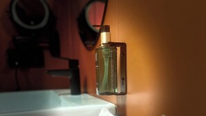A bathroom with a hand soap dispenser mounted on the wall, a tissue box, and a reed diffuser.