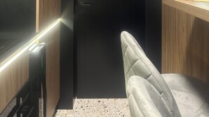 A modern interior with a dark door, wooden paneling, and a seating area with a light-colored cushion.