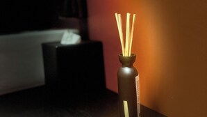 A small, dark-colored vase with a label on a wooden surface.