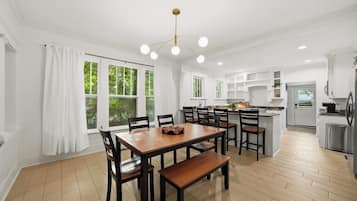 A modern kitchen with a dining area, large windows, and a central island.