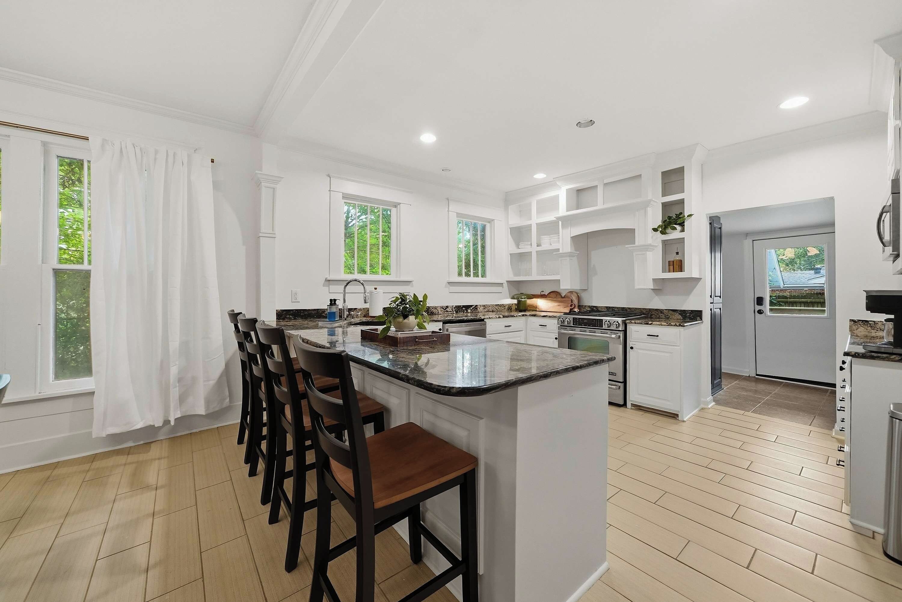 A modern kitchen with a central island, bar stools, and built-in cabinetry.