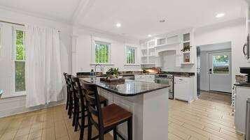A modern kitchen with a central island, bar stools, and built-in cabinetry.