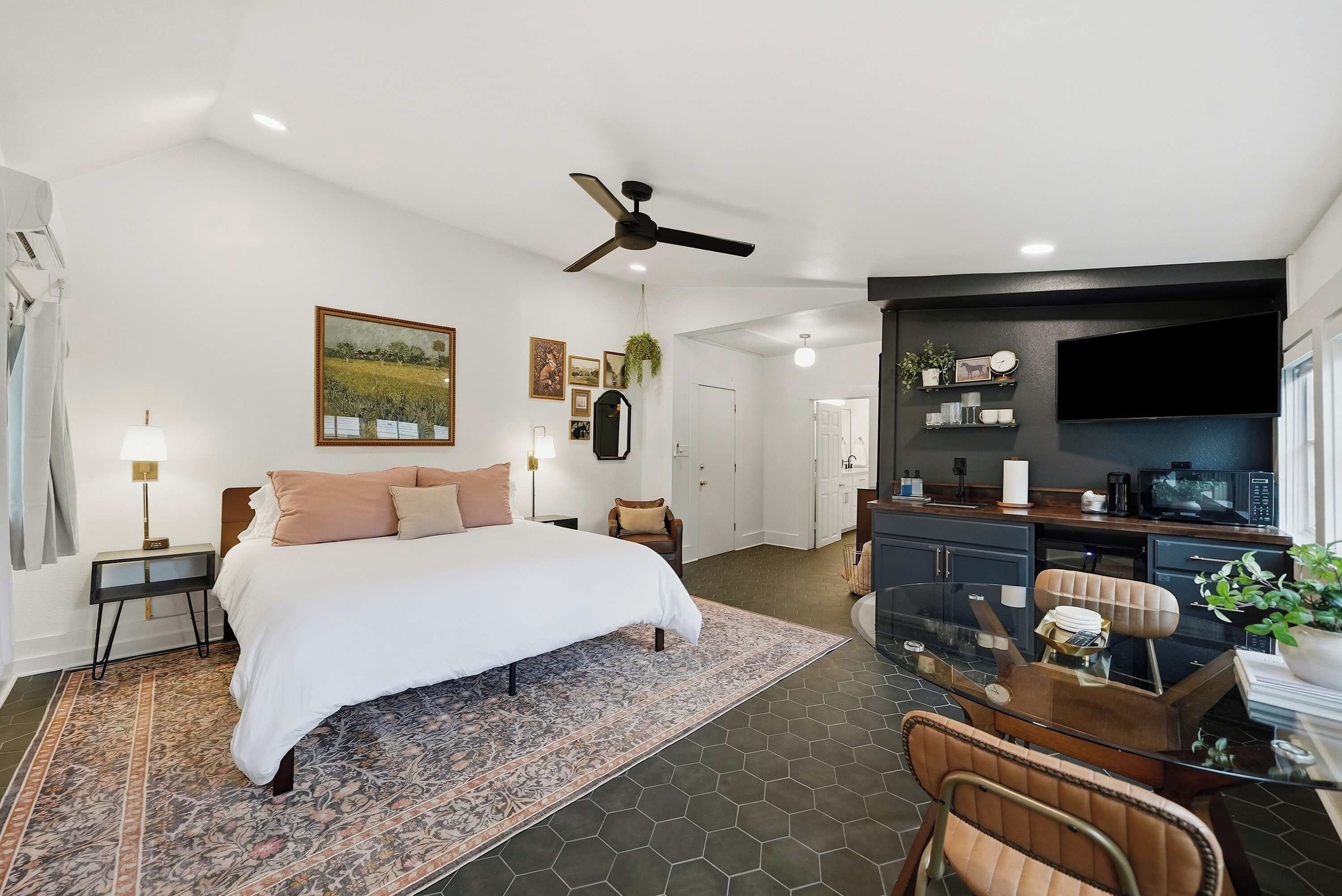 A modern bedroom with a large bed, a desk area, and a ceiling fan.