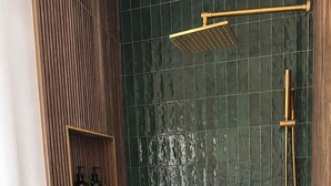 A bathroom with a shower, a wall-mounted shelf with toiletries, and a drain. - Designer A-Frame, Hot Tub, Mountain Views, Game Room (Divide)