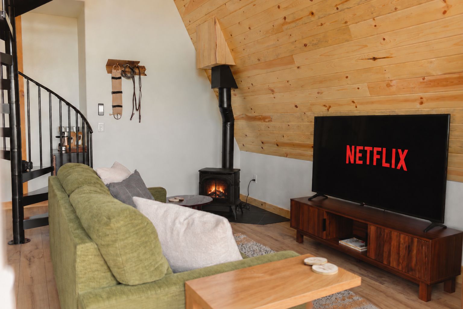 Un salon chaleureux avec un canapé vert, un meuble TV en bois et une cheminée.