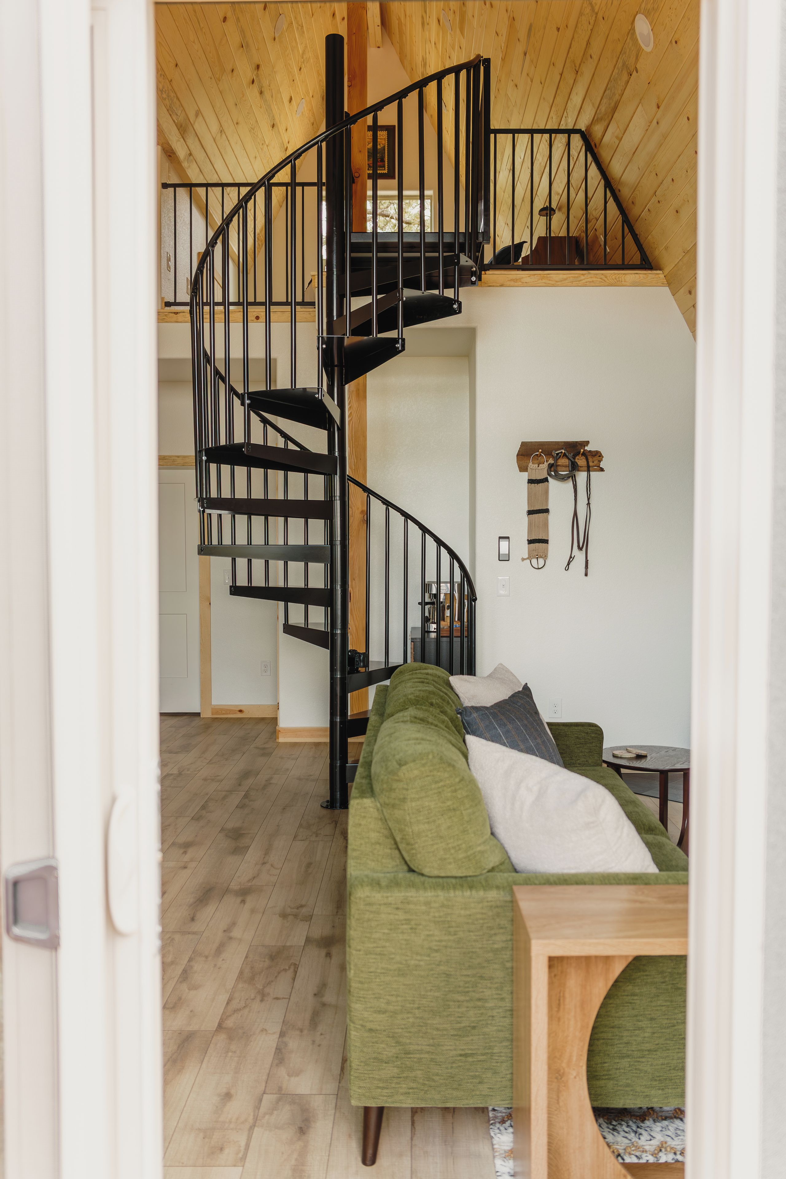 A modern interior with a spiral staircase, a green sofa, and a wooden dining table.