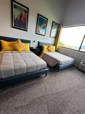 Ein Hotelzimmer mit zwei Betten, einem großen Fenster und Wandkunst.