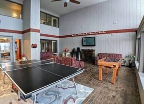 En rummelig stue med et pingpongbord, pejs og behagelige siddepladser.