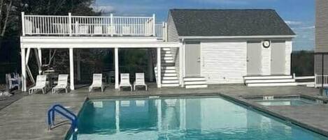 A swimming pool with lounge chairs and a small building with a garage.