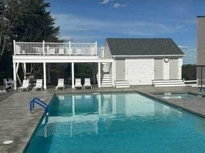 Ein Schwimmbecken mit Liegestühlen und ein kleines Gebäude mit Garage.