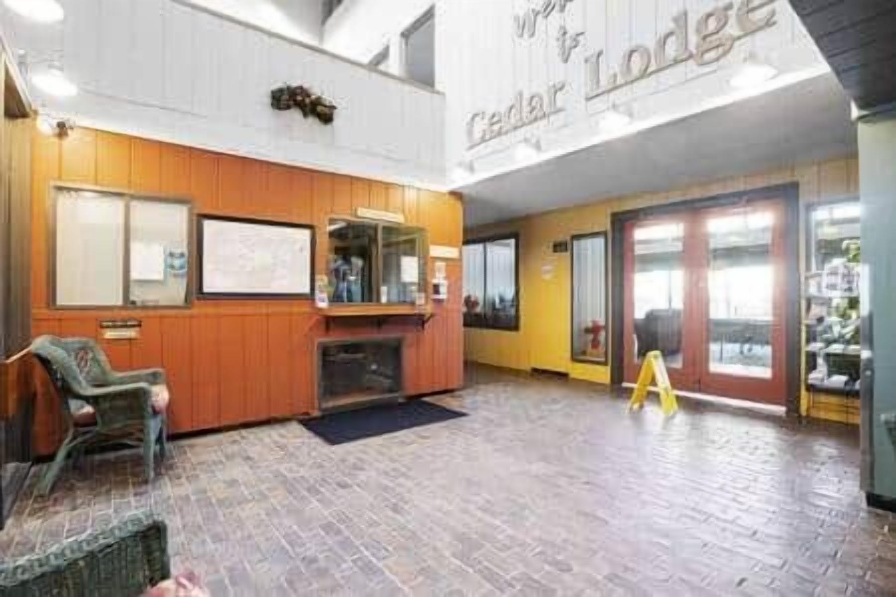 Un hall d’entrée avec un comptoir de réception en bois, un espace salon et une grande enseigne « Cedar Lodge ».