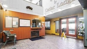 Um hall de entrada com balcão de madeira, área de estar e um grande letreiro Cedar Lodge.