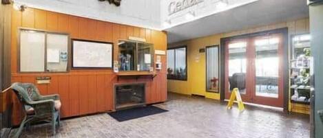A lobby with a wooden reception desk, a seating area, and a large Cedar Lodge sign.