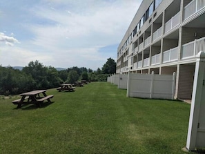 Ein Gebäude mit mehreren Balkonen und einer Rasenfläche mit Picknicktischen.