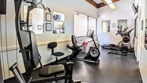 A gym with exercise equipment including a bench press, a stationary bike, and a treadmill. - Amazing Condo 2 bedroom 2 bath with Lake Winni Views (Laconia)