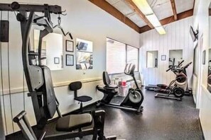 A gym with exercise equipment including a bench press, a stationary bike, and a treadmill. - Amazing Condo 2 bedroom 2 bath with Lake Winni Views (Laconia)