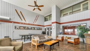 A spacious lounge area with a brick floor, wooden furniture, and a ceiling fan. - Amazing Condo 2 bedroom 2 bath with Lake Winni Views (Laconia)