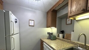 A compact kitchen with a refrigerator, dishwasher, granite countertop, sink, and wooden cabinets. - Amazing Condo 2 bedroom 2 bath with Lake Winni Views (Laconia)