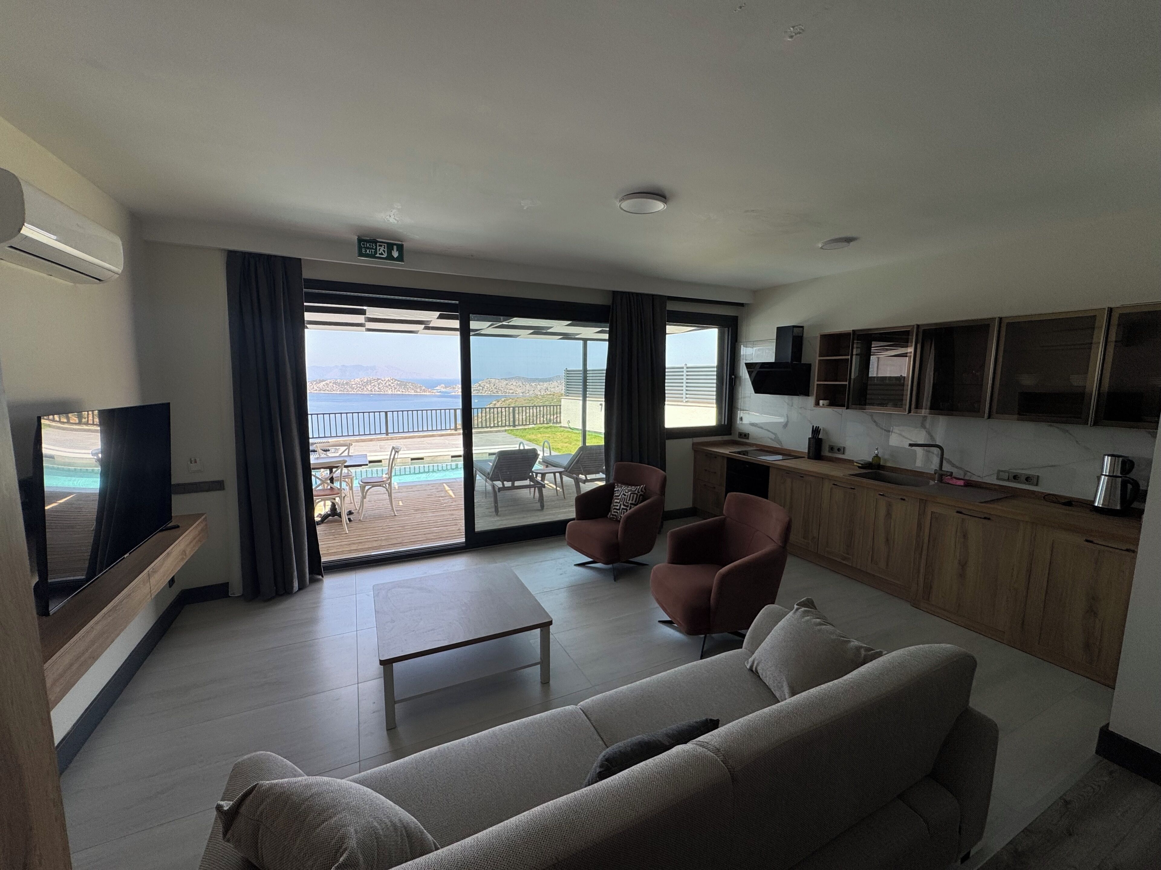 Ein modernes Wohnzimmer mit Sofa, Fernseher und Meerblick.