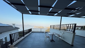 A rooftop terrace with a table and chairs, a view of the sea, and a building with a sloped roof. - La Mer Villa Hotels (Marmaris)