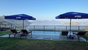 A poolside area with lounge chairs and umbrellas, overlooking a body of water and distant mountains. - La Mer Villa Hotels (Marmaris)