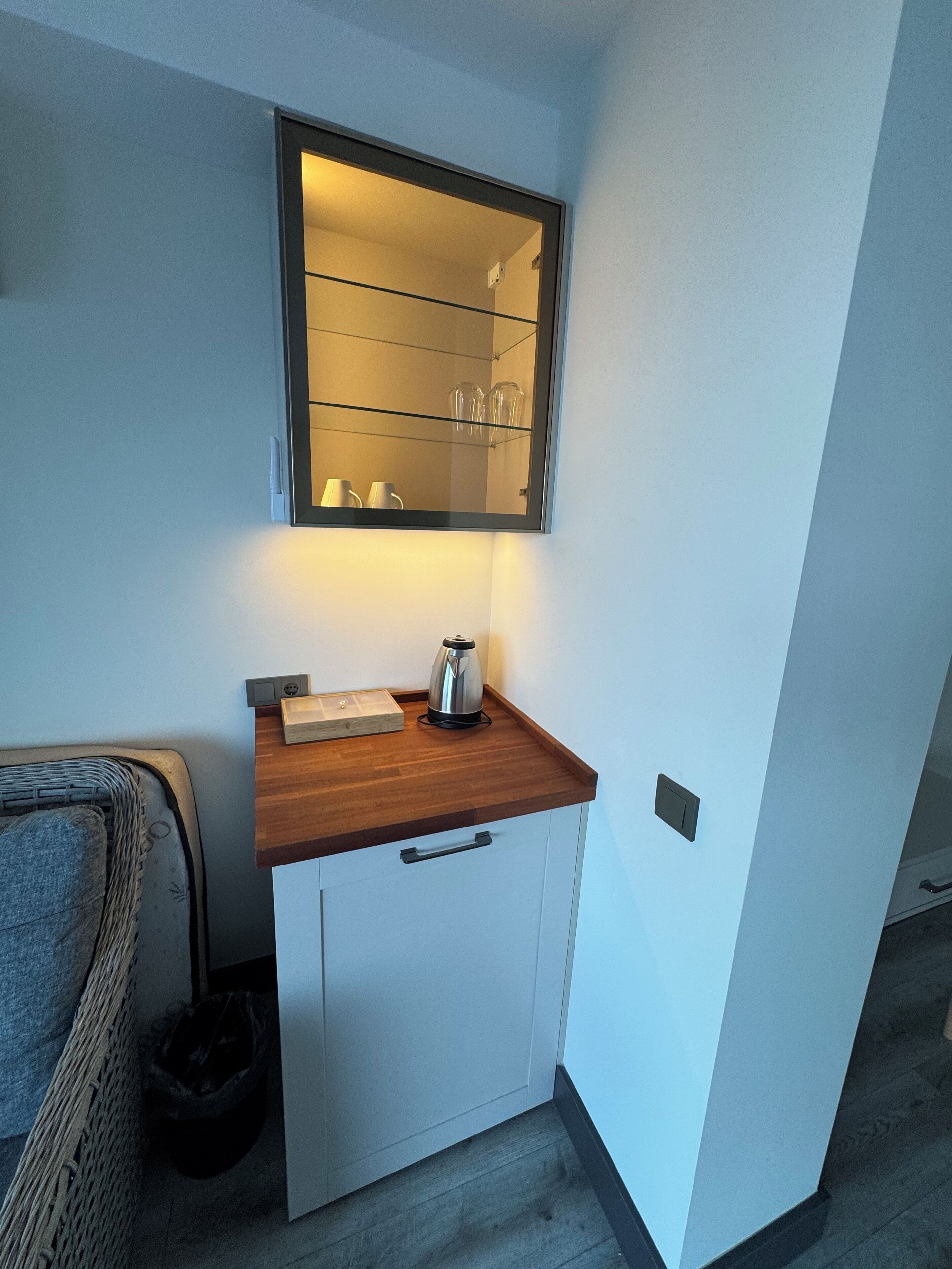 Eine kleine Küchenzeile mit einer Holzausziehtafel, einer Kaffeemaschine und einem Spiegel darüber.