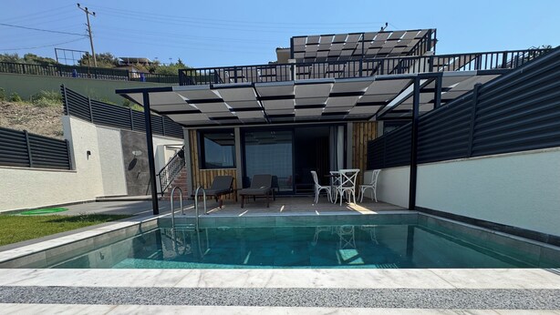A swimming pool with a covered patio area, outdoor furniture, and a view of a residential building. - La Mer Villa Hotels (Marmaris)