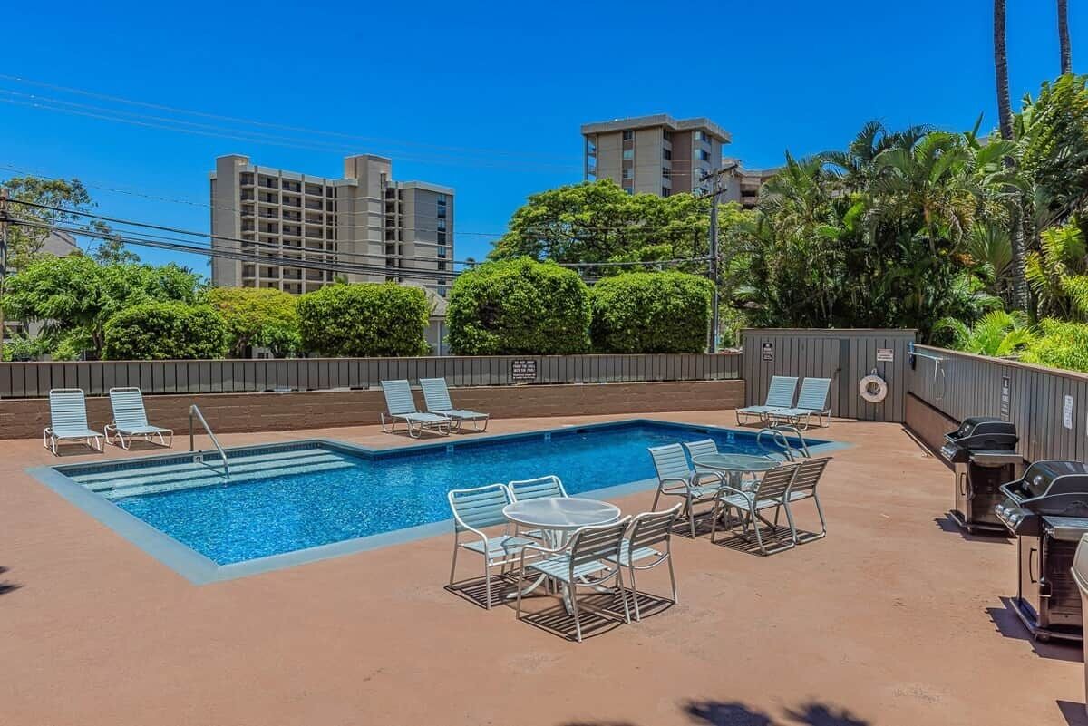 Una piscina sul tetto con poltronne prendisole e barbecue.