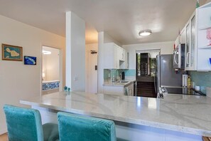 A modern kitchen with white cabinets, a central island, and a view into the dining area.