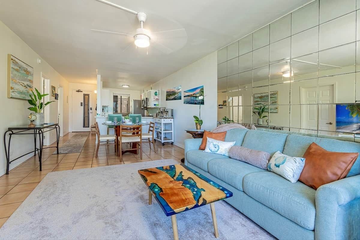 A modern living room with a light blue sofa, a coffee table with a unique design, and a dining area with chairs and a table.