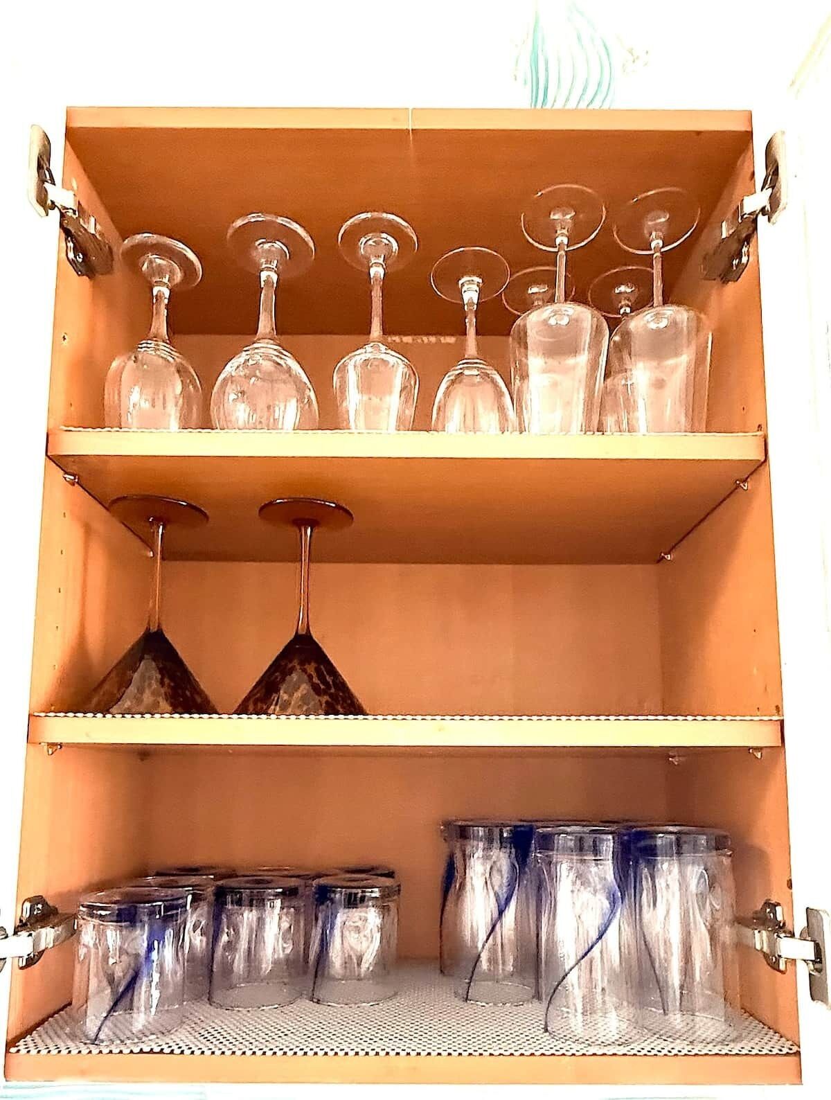 A storage cabinet with multiple shelves holding various glassware and containers.