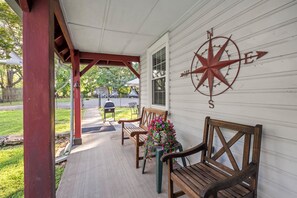 A porch with wooden benches and a compass wall decoration.