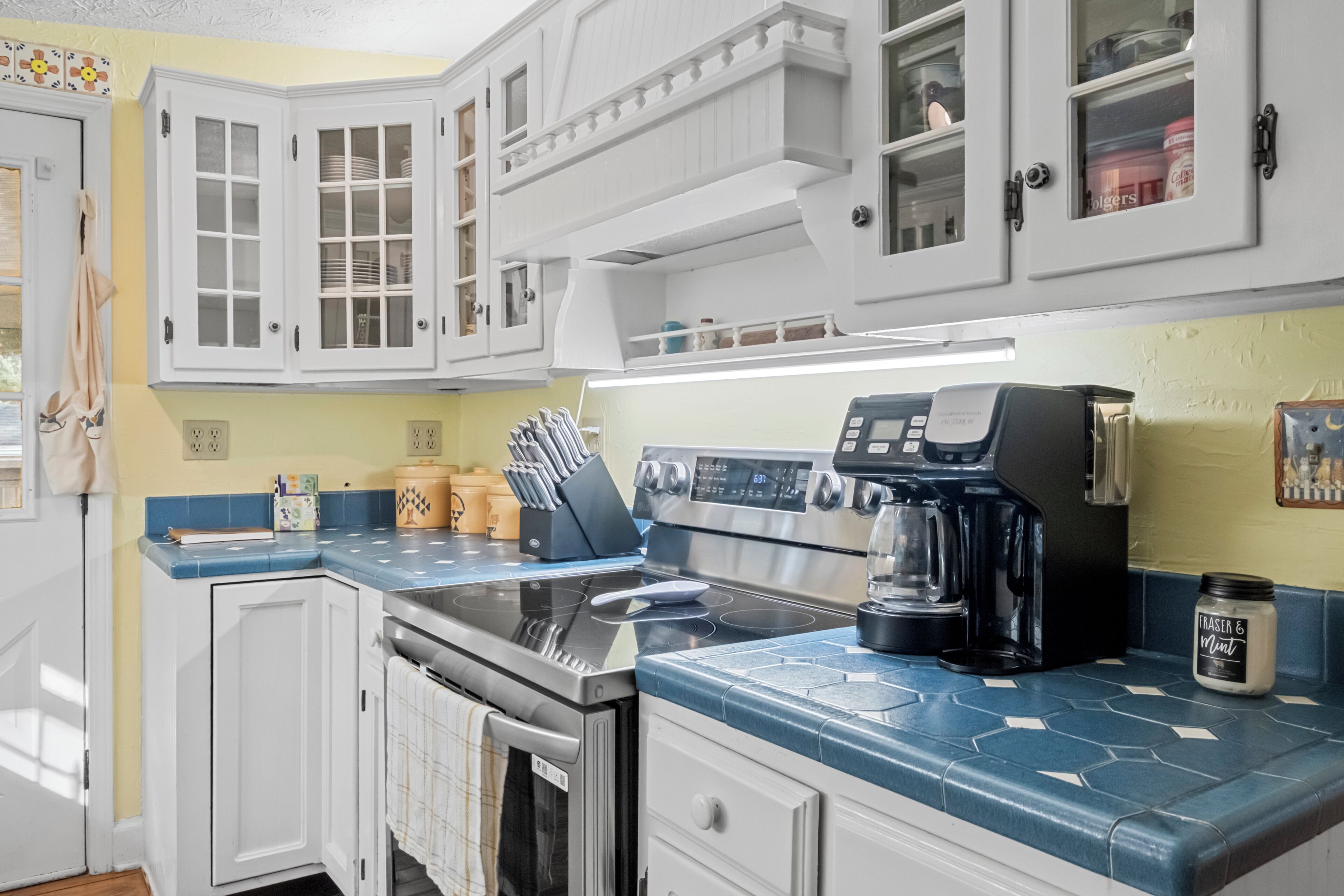 A kitchen with white cabinets, a stainless steel stove, and a coffee maker.
