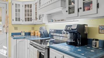 A kitchen with white cabinets, a stainless steel stove, and a coffee maker.